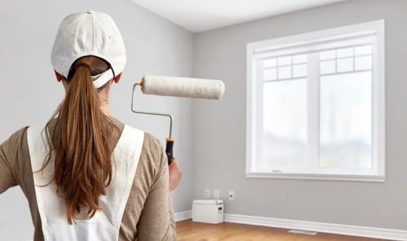 young woman with a paint brush ready to paint a room