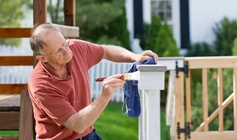 old man painting a garden fence