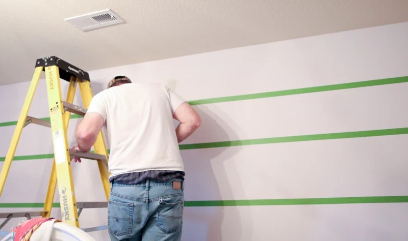 young man painting beautiful stripes on a wall