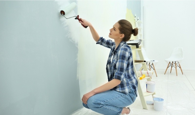 woman coloring a wall with a paint brush