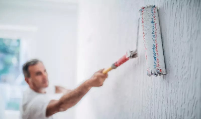 young man coloring a wall with a roller