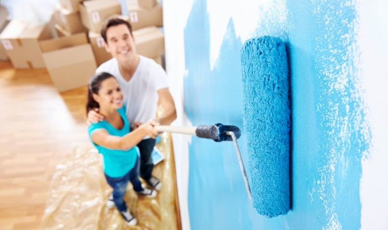 couple coloring a wall with a roller