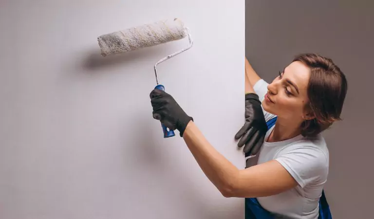 woman coloring a wall with a roller