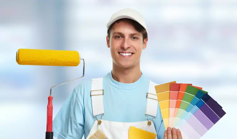 young professional holding a paint brush and color shades in hands