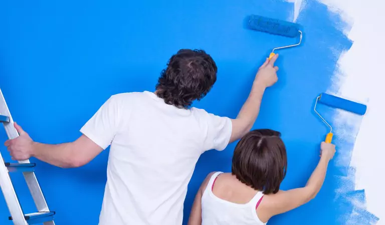 young couple coloring a wall with roller