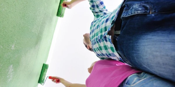 a couple is using green paint on wall